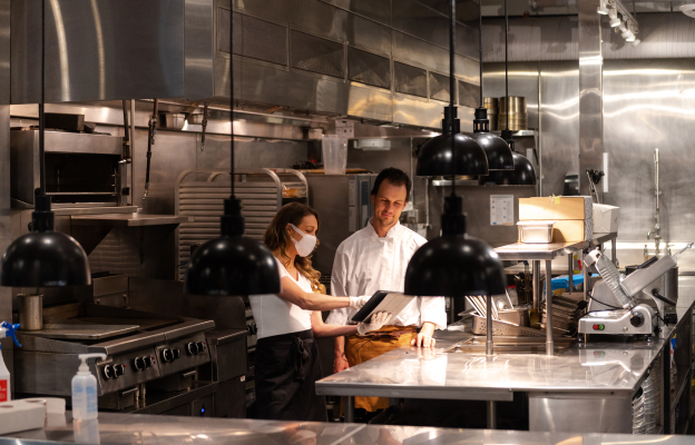 Chefs and inspector review checklist in kitchen